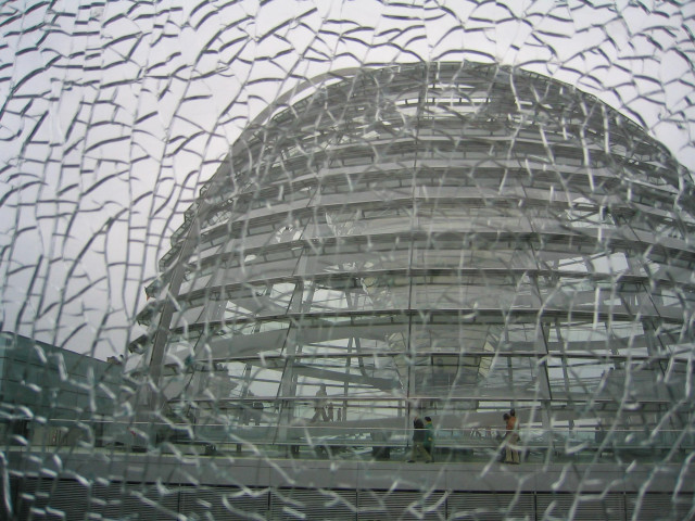 Die Kuppel des Deutschen Bundestags - fotografiert durch eine geplatzte Scheibe auf dem Dach. Der Eindruck entsteht, dass das Bild im nächsten Augenblick in tausend Scherben zerspringen könnte. 