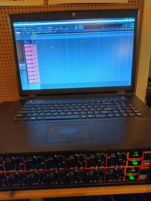 Photo of a laptop running Ardour on Debian on top of two 8-channel ADAT units that are connected to the laptop through a RME Digiface USB.