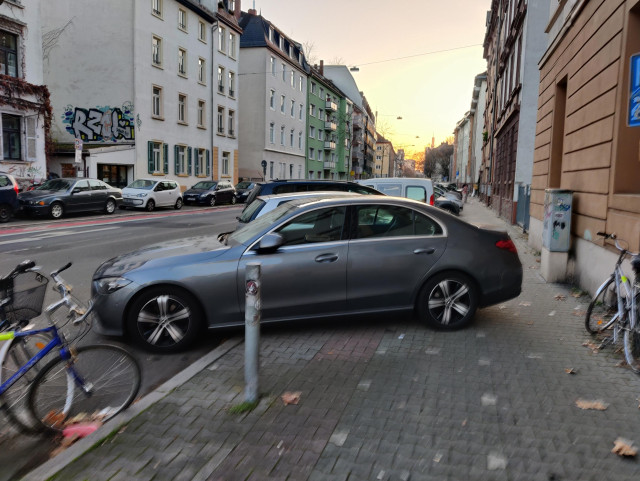 Ein grauer Mercedes parkt ist auf einem Parkplatz so weit nach hinten gefahren, dass er den Platz auf dem Bürgersteig massiv einschränkt 