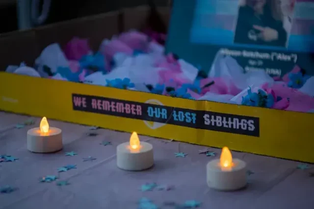 A box containing photograph and pink, blue and white confetti bears the mesage WE REMEMBER OUR LOST SIBLINGS.  