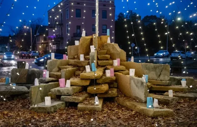 A stone monument surrounded by fairy lights, covered in candles
