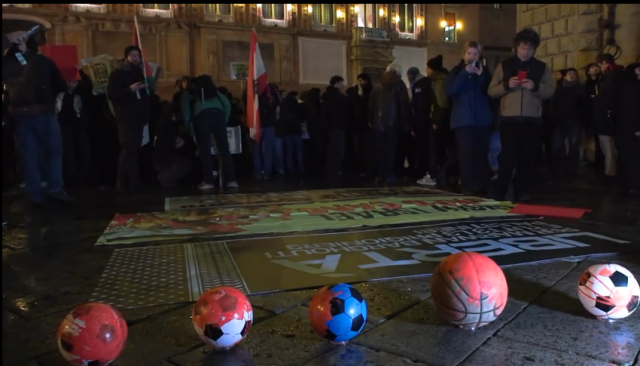 Crowds gathered around some banners laid  on the ground, along with a few footballs and a basketball painted in red.