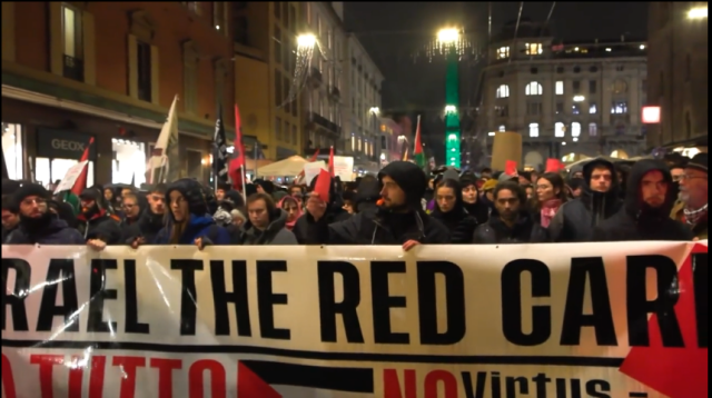 Huge crowd marching through Bologna, many of whom are holding red cards.