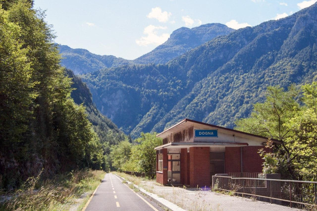 Radweg auf der ehemaligen Bahntrasse der Pontebbana, am Rand ist noch das ehemalige Stationsgebäude von Dogna zu sehen.