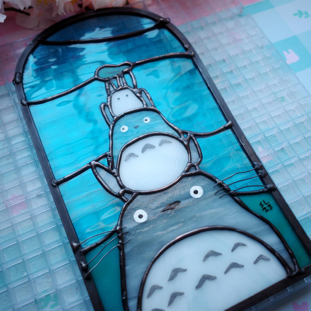 Stained glass art featuring 3 Totoro stacked on top of each other.