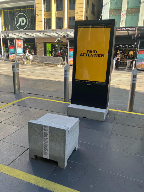 A screen that says paid attention. In front of the screen is a blocky uncomfortable chair 