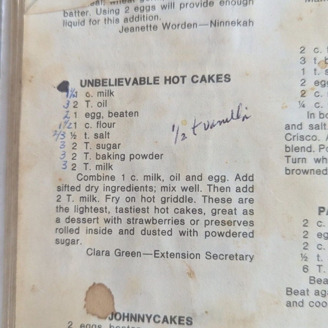 Cookbook page stained from use featuring a recipe for hot cakes with handwritten ingredient adjustments in pen.