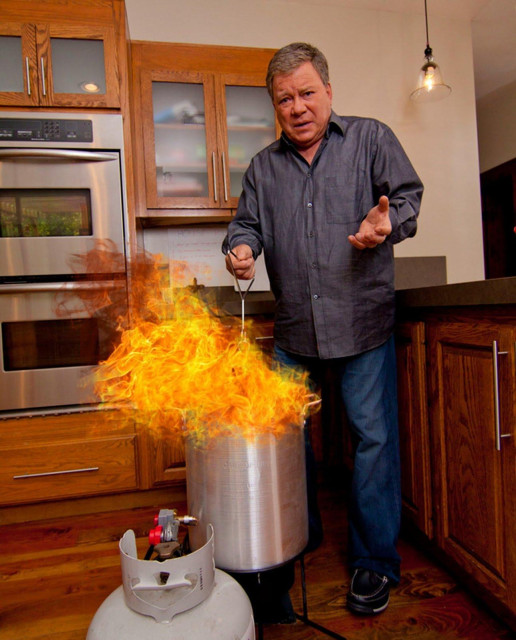 William Shatner holding a turkey that is deep fat frying with flames around the top.From  a video highlighting the hazards of deep-frying a turkey. Photo: State Farm