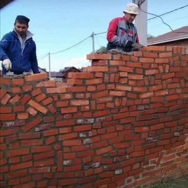 Photo of two brick layers laying bricks in a haphazardly way. The bricks aren't all flat, as such what should be straight rows is anything but.