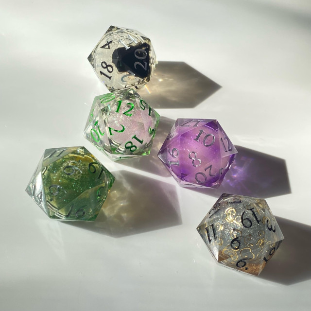 A d20 set of liquid cores:
One clear with white glitter and a black cloud
One clear with pink glitter and green tendrils
One clear with green glitter and shimmer
One lavender with purple shimmer and green flakes
One clear with silver glitter, gold filigree and a gold cloud

