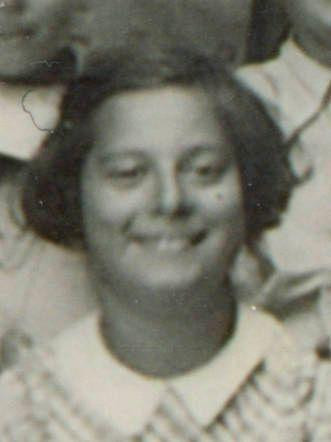 Vintage black and white photo of a smiling girl with short hair, wearing a striped garment.