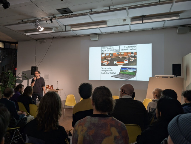 Public listening to Aymeric, main slide with a meme: “STOP MAKING NEW TECHNOLOGY we can run the whole world with a bunch of ThinkPads”