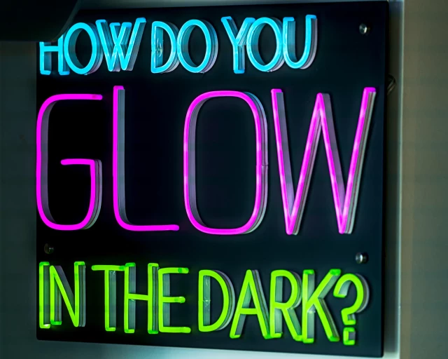 Auf einer schwarzen Fläche steht in leuchtenden Buchstaben geschrieben: How do you glow in the Dark?
.
On a black surface in glowing colourful letters this is written: How do you glow in the Dark?
.
