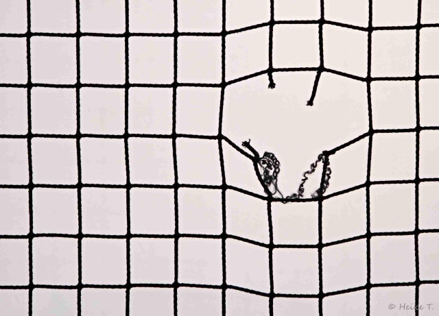 Netz eines Fußballtores mit einem Loch.