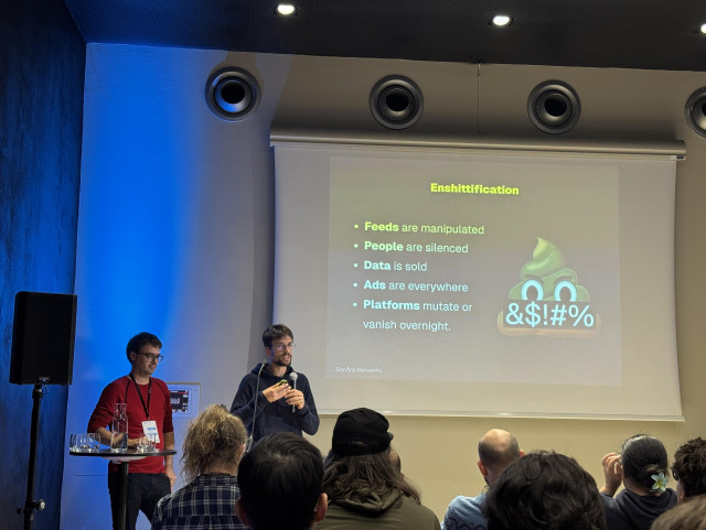 The bonfire team at SFSCon 2025, presenting a slide titled “Enshittification”. On the left hand side of the slide, a bulleted list with the following sentences: “feeds are manipulated, people are silenced, data is sold, ads are everywhere, platforms mutate or vanish overnight”. On the right hand side, a sh!t emoji