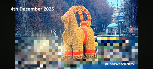 The Gävle Goat on the morning of 4th of December 2025. 

Picture shows a large straw effigy of a goat with red trimmings surrounded by a fence. Behind the goat a tree lined esplanade and the Gävle theatre are visible. Parts of the image are pixelated to obscure people passing by.

Picture from YouTube Live Feed. 