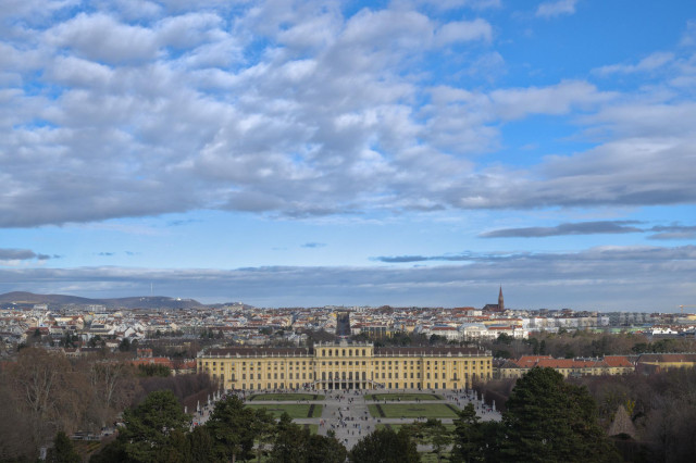 Blick von einem Berg hinab auf die Stadt Wien und das Schloss Schönbrunn. 