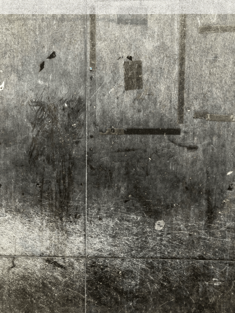 Colour photo of a flat dark grey stone surface with lots of signs of wear and tear.