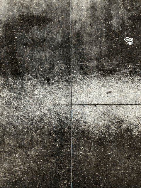 Colour photo of a flat dark grey stone surface with lots of signs of wear and tear.