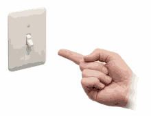 A hand reaches toward a light switch and flips it from the off position to the on position in one smooth motion.