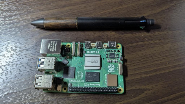 A Raspberry Pi on a desk with a pen next to it for scale (the pen is much longer than the Raspberry Pi)