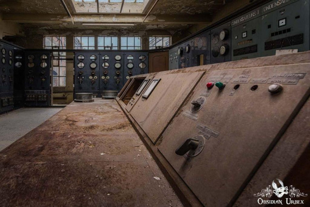 A derelict industrial control room with peeling paint. A panel reads "CONDENSATEURS" and has red/green buttons and toggles.