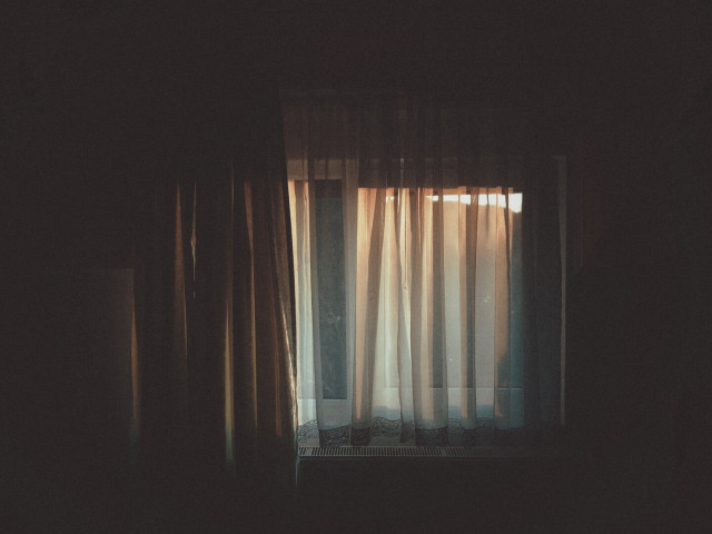 The evening sun makes its way through the window and disappears into the dark room.