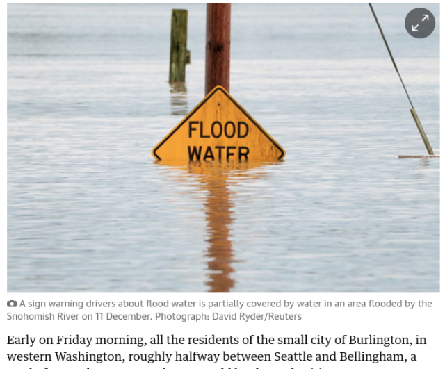 Photo of a "FLOOD WATER" sign which is flooded up to the bottom of the words "WATER" 