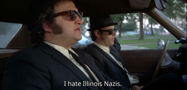 The Blues Brothers sitting in their car, with subtitles showing one of them saying "I hate Illinois Nazis"