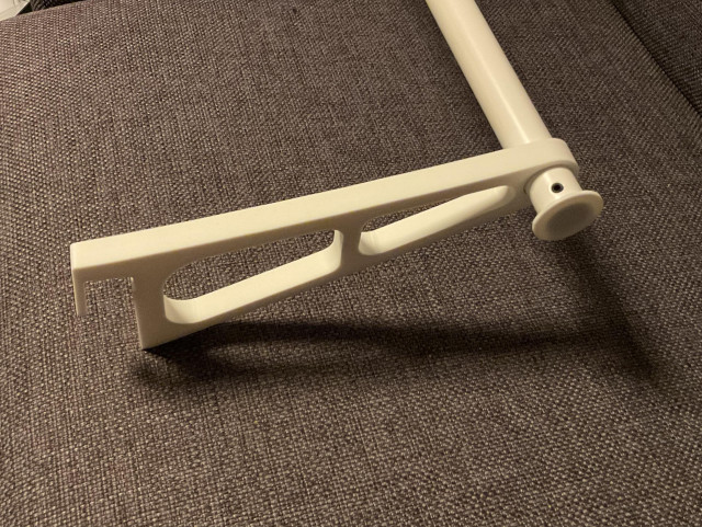 Photo of a bracket with one end of a clothes rod visible. The rod is a white metal tube. The of the rod end is secured with a white PLA-Plug that has a diameter larger than the rod and the bracket, so it can’t slip out of the bracket.
The plug is held in place on the rod by a small black set screw that‘s visible outside on the rod.