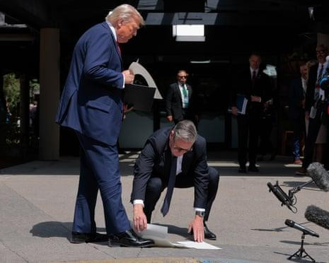 Picture of Starmer crouching at the feet of Donald Trump to pick up his papers for him.