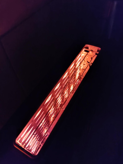 Blick in einen heizenden Toaster, man sieht orangene Heizfäden, rund herum ist es dunkel