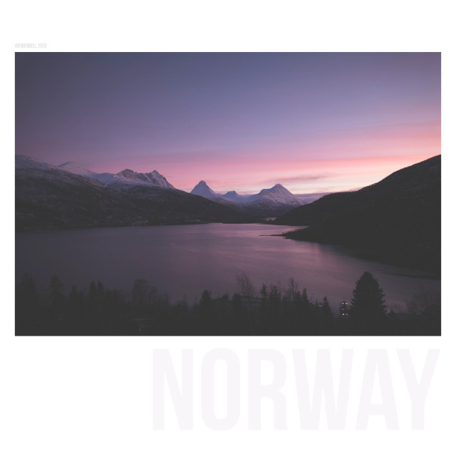 Wide angle scene of the fjord at Grov, with distant peaks rising into the pink clouds.