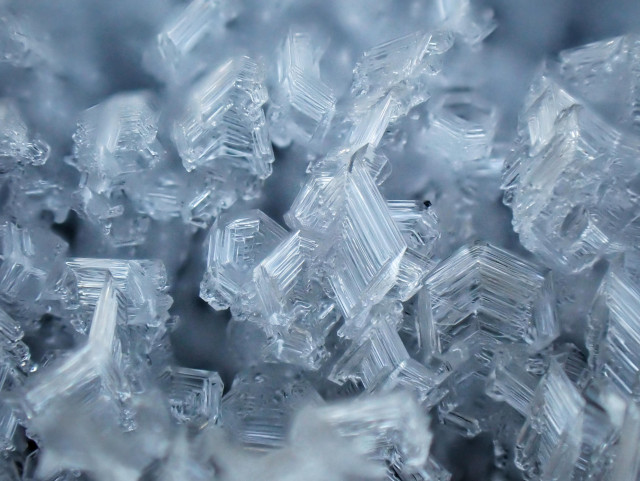 Close-up image showing the delicate, fascinating structure of hoar frost crystals formed on an iron gate
