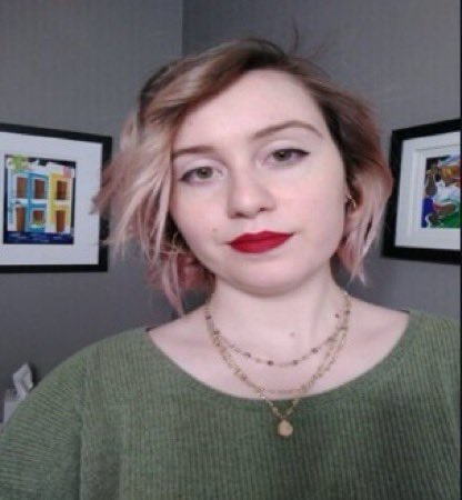 Photo of a blonde woman in a green shirt with a gold necklace and red lipstick 