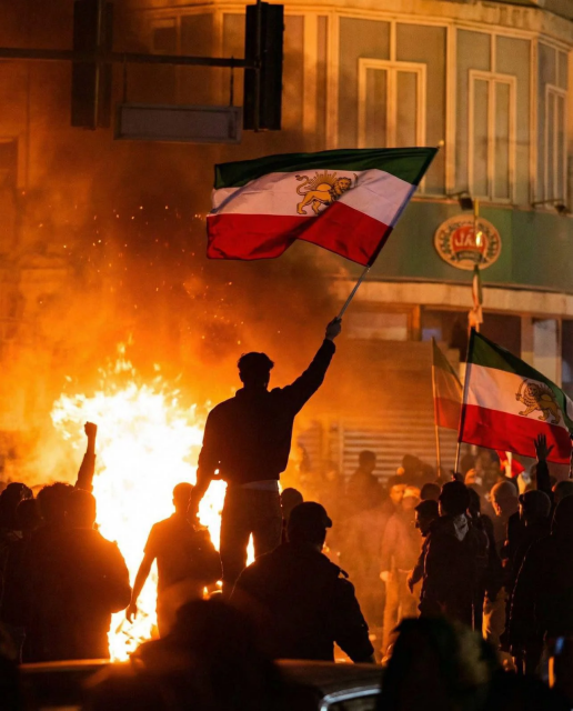 Crowds at night with a bonfire waving Lion and Sun Flags