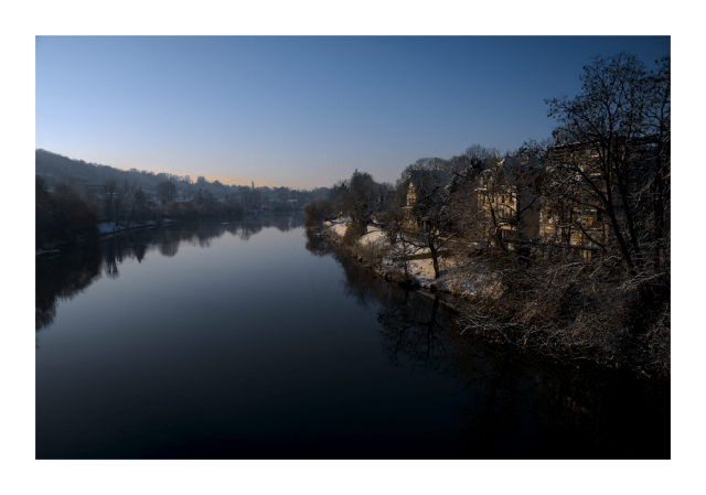 Morning light photography
snowy banks of the river curving towards the right in the background, sunrise to the left, some villas to the right receiving that gift.