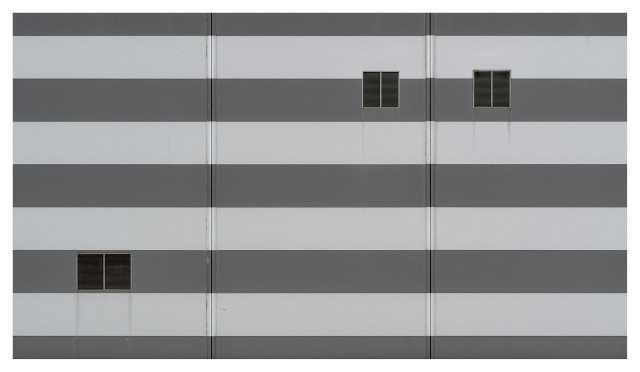 En liggande monokrom bild på en randig vägg med 3 ventilationsluckor, 2 uppe till höger och en nere till vänster.