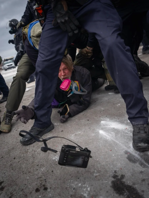Getty photojournalist John Abernathy is seen face down on ground pinned & surrounded by federal agents. His arm is outstretched & his camera is midair as he tossed it to another photographer so it wouldn't be confiscated. Photo by Pierre Lavie.