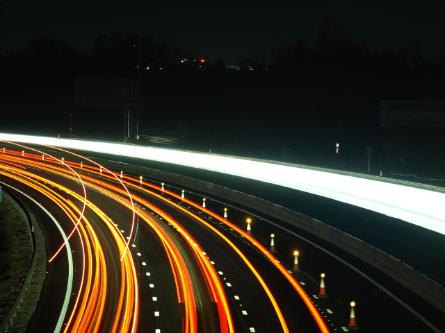 A slow shutter photo of the M27 showing lines of car lights going round a bend to the left. 