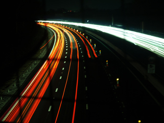 Slow shutter through the metal fence of the motorway traffic. 