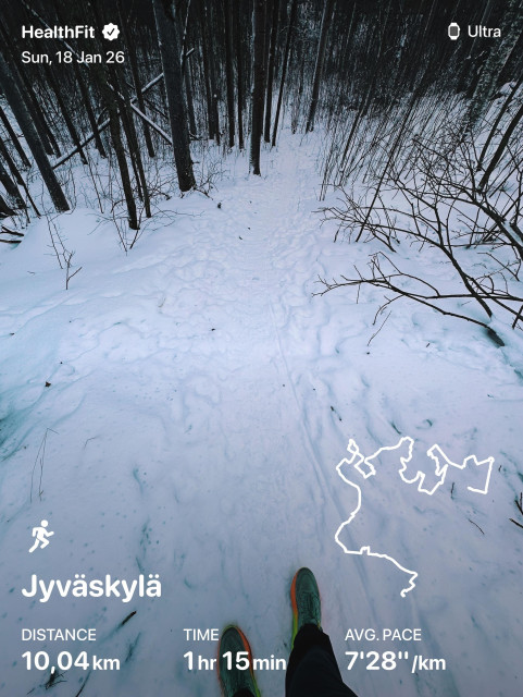 Person's feet walking on a snow-covered trail through a forest, with a small map and exercise stats overlay at the bottom.