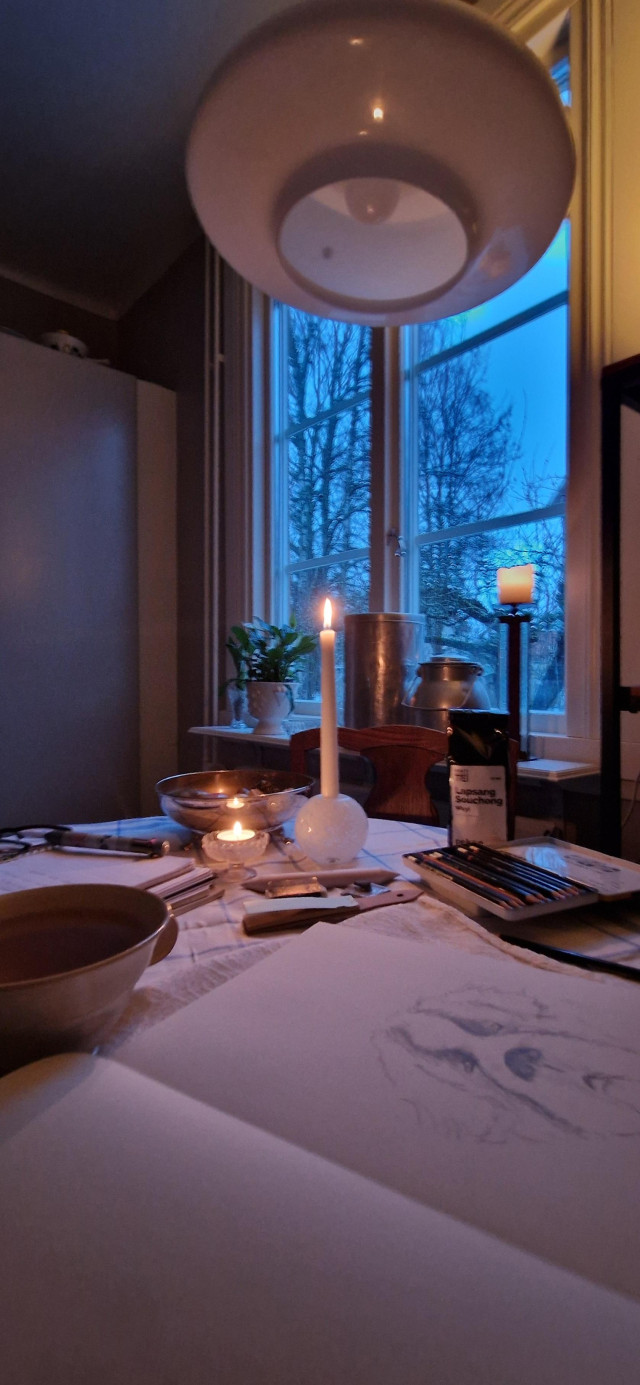 Skissar under levande ljus och dricker te.