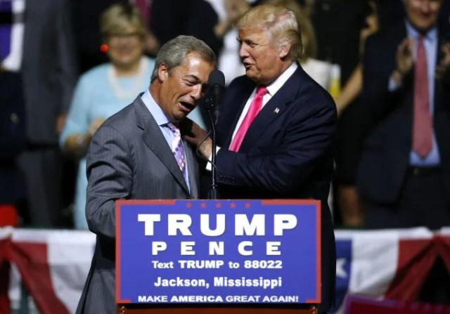 Trump and Farage standing behind a TRUMP PENCE lectern on the campaign trail in Jackson, Mississippi, looking like bezzies. Trump is giving Farage a pat on the back and they both look very pleased with themselves.