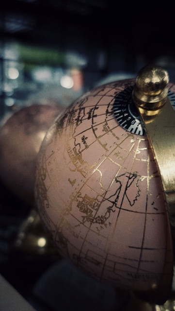 Two globes, coloured in pink and kept in golden frames, on a store shelf.