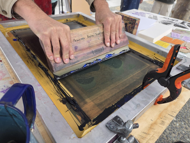 Hand of an artist working on a screen printed poster.
