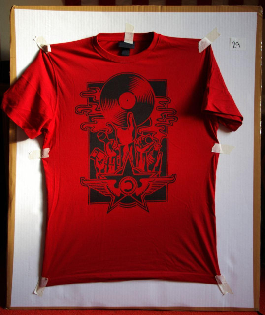 A stencilled red T-shirt showing a ‘copyleft’ design, including a star, some wings, and a bunch of hands holding up various items to represent fields which might benefit from more open information sharing: music, photography, science, software, etc.