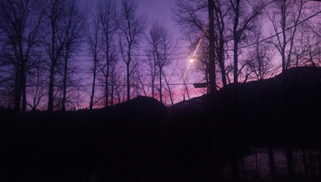 Silhouette mountains and trees, obscure view of the river. Pink and purple sky