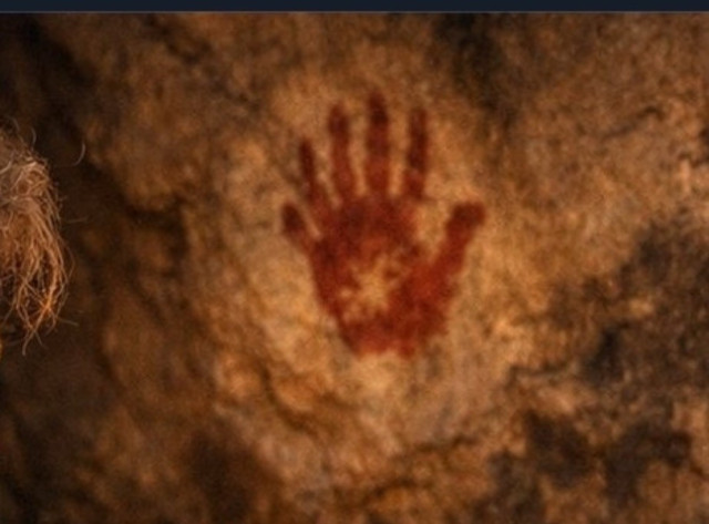 An ancient red handprint is visible on a rocky surface, suggesting prehistoric art. The hand  on the cave wall has 6 fingers, and is supposed to show Neanderthal life. The source and more is here: https://bsky.app/profile/dbellingradt.bsky.social/post/3mcgzpippik2m 
