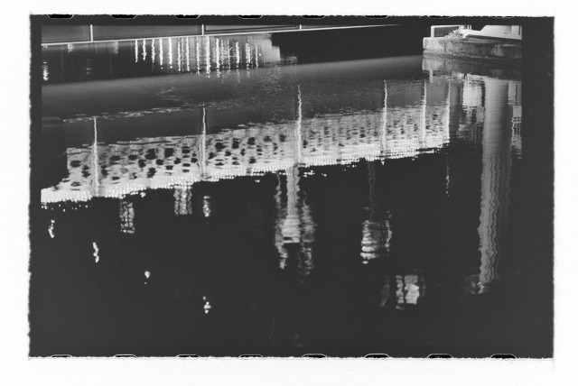 Negative scan of the reflection of a bridge in a canal.